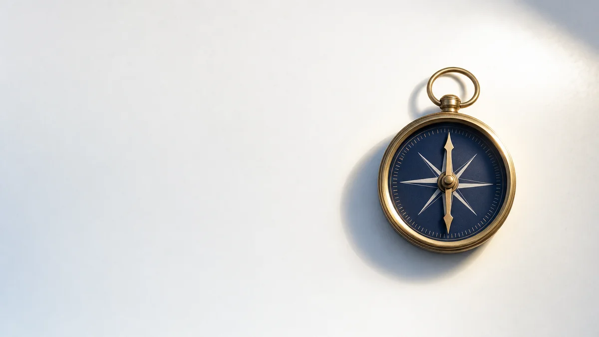 A single brass compass resting on a matte white surface, needle pointing north